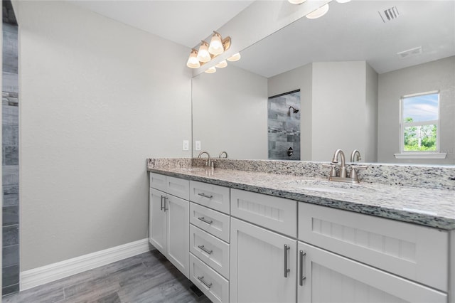 8270 Cook Ct, Port Charlotte, FL 33981 - bathroom featuring double vanity, baseboards, wood finished floors, and a tile shower