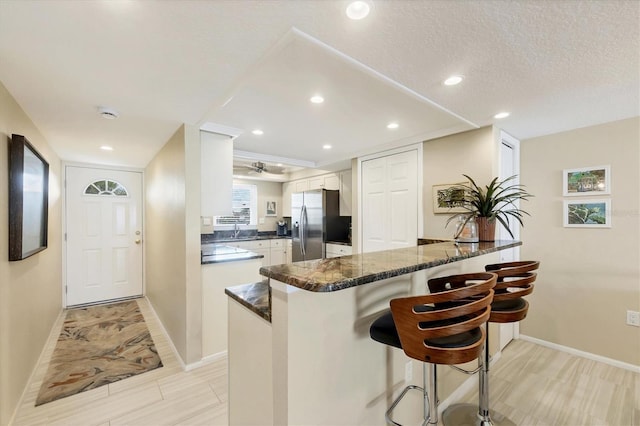 2700 N Beach Rd Unit B205, Englewood, FL 34223 - kitchen featuring stainless steel fridge with ice dispenser, a kitchen bar, a peninsula, white cabinets, and baseboards
