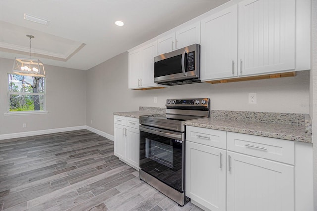 13529 Boatbill Ln, Port Charlotte, FL 33981 - kitchen with appliances with stainless steel finishes, light wood-style flooring, a raised ceiling, white cabinets, and recessed lighting