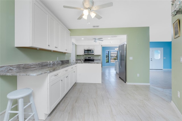 23 Bunker Cir, Rotonda West, FL 33947 - kitchen with stainless steel appliances, a ceiling fan, white cabinetry, light stone counters, and a sink