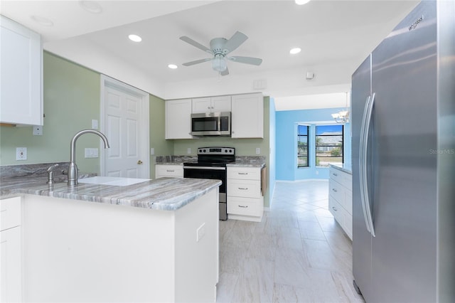 23 Bunker Cir, Rotonda West, FL 33947 - kitchen with appliances with stainless steel finishes, light stone countertops, a ceiling fan, white cabinetry, and a peninsula