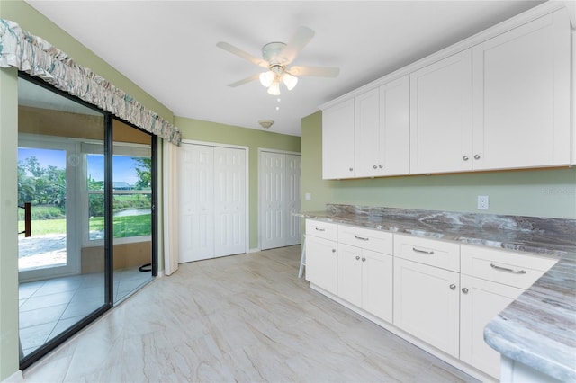 23 Bunker Cir, Rotonda West, FL 33947 - kitchen featuring ceiling fan, white cabinets, and light stone counters