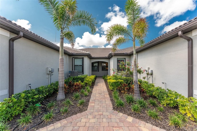 13859 Vadini St, Venice, FL 34293 - view of exterior entry with stucco siding, a tiled roof, and central AC