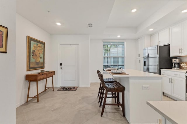 12470 Wellen Golf St Unit 108, Venice, FL 34293 - kitchen with stainless steel refrigerator with ice dispenser, white cabinets, a center island, a breakfast bar, and recessed lighting
