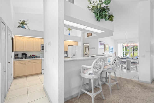 116 Tournament Rd, Rotonda West, FL 33947 - kitchen with white appliances, light brown cabinets, a high ceiling, light countertops, and a breakfast bar area
