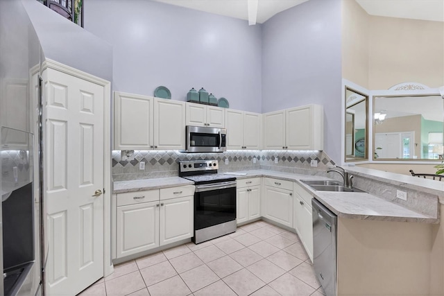 4225 Fairway Dr, North Port, FL 34287 - kitchen featuring appliances with stainless steel finishes, a sink, a high ceiling, decorative backsplash, and light tile patterned floors