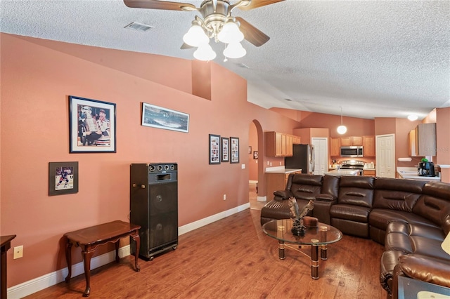 5510 Moongate Rd, Spring Hill, FL 34606 - living room with lofted ceiling, a textured ceiling, a ceiling fan, arched walkways, and light wood-type flooring