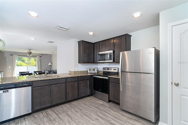2408 Bonanza Ln, North Port, FL 34286 - kitchen featuring stainless steel appliances, a sink, dark brown cabinets, a ceiling fan, and light stone counters