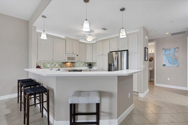 11100 Hacienda Del Mar Blvd Unit G-304, Placida, FL 33946 - kitchen featuring stainless steel fridge, white microwave, light tile patterned flooring, decorative backsplash, and a peninsula
