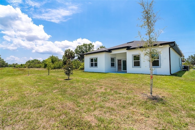 398 Sunset Rd N, Rotonda West, FL 33947 - back of house with stucco siding, a lawn, and cooling unit