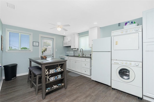859 E 2nd St, Englewood, FL 34223 - kitchen featuring white appliances, stacked washer / drying machine, ceiling fan, dark wood-style flooring, and white cabinets