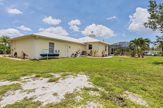 8127 Consul St, Port Charlotte, FL 33981 - back of property with a yard, stucco siding, glass enclosure, and a metal roof