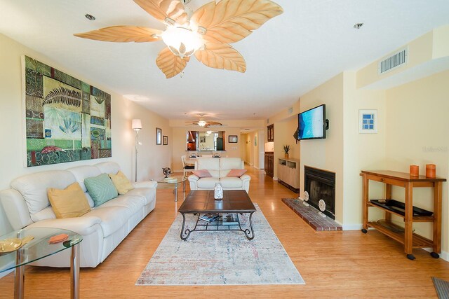 7303 Jessie Harbor Dr Unit 7303, Osprey, FL 34229 - living area featuring a ceiling fan, light wood-style flooring, and a fireplace with raised hearth