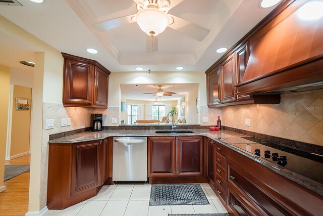 7303 Jessie Harbor Dr Unit 7303, Osprey, FL 34229 - kitchen with stainless steel dishwasher, a ceiling fan, premium range hood, a raised ceiling, and dark stone countertops