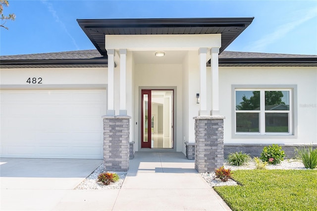 482 Sunset Rd N, Rotonda West, FL 33947 - view of exterior entry with stucco siding, roof with shingles, concrete driveway, and a garage