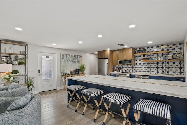 7530 Whitcomb St, Englewood, FL 34223 - kitchen with stainless steel appliances, a sink, a breakfast bar area, light wood finished floors, and recessed lighting