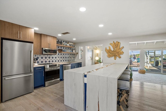 7530 Whitcomb St, Englewood, FL 34223 - kitchen featuring appliances with stainless steel finishes, light countertops, open shelves, backsplash, and light wood-type flooring