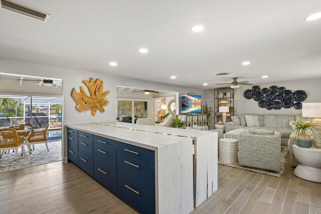 7530 Whitcomb St, Englewood, FL 34223 - kitchen with ceiling fan, blue cabinetry, wood finished floors, open floor plan, and recessed lighting