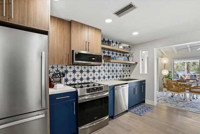 7530 Whitcomb St, Englewood, FL 34223 - kitchen with appliances with stainless steel finishes, a sink, blue cabinetry, light wood finished floors, and recessed lighting