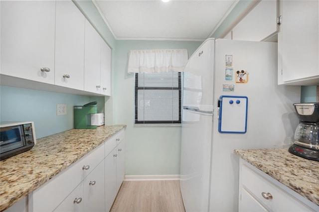 1501 Beach Rd Unit 310, Englewood, FL 34223 - kitchen with freestanding refrigerator, white cabinets, light wood-style flooring, and baseboards