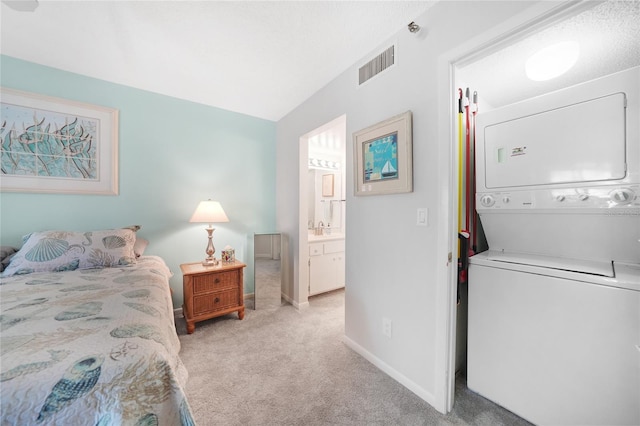1501 Beach Rd Unit 310, Englewood, FL 34223 - bedroom with stacked washing machine and dryer, light carpet, baseboards, a sink, and ensuite bath