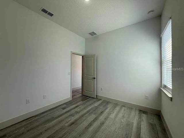 311 Yule St, Port Charlotte, FL 33953 - empty room with wood finished floors, healthy amount of natural light, baseboards, and a textured ceiling