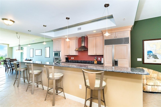 1375 Beach Rd Unit 201, Englewood, FL 34223 - kitchen featuring wall chimney exhaust hood, built in appliances, a breakfast bar, dark stone counters, and a large island