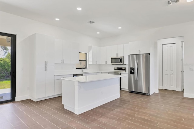 10242 Hallendale Dr, Port Charlotte, FL 33981 - kitchen with stainless steel appliances, a sink, light countertops, white cabinetry, and a center island