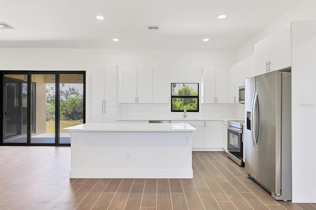 10242 Hallendale Dr, Port Charlotte, FL 33981 - kitchen with stainless steel appliances, a sink, a kitchen island, light countertops, and white cabinetry