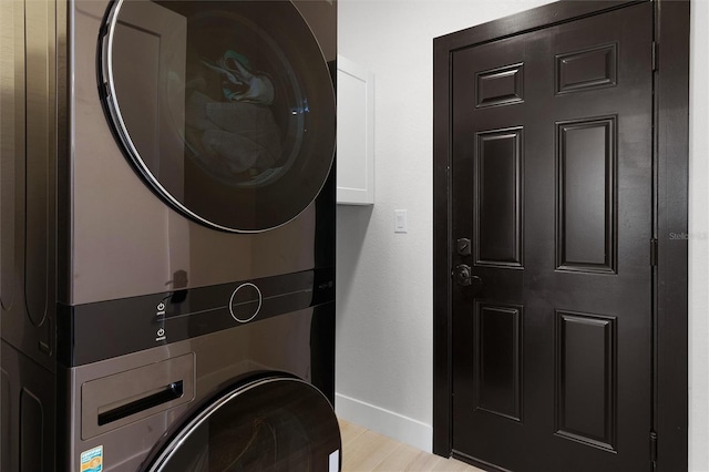 10454 Atenia St, Port Charlotte, FL 33981 - laundry room featuring stacked washer / drying machine, baseboards, cabinet space, and light wood-style flooring