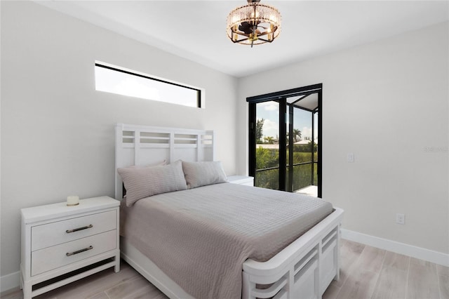 10454 Atenia St, Port Charlotte, FL 33981 - bedroom with a chandelier, baseboards, access to exterior, and light wood-style flooring