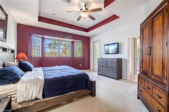13091 Sandy Key Bnd Unit 104, North Fort Myers, FL 33903 - bedroom with a tray ceiling, light colored carpet, a ceiling fan, access to exterior, and baseboards