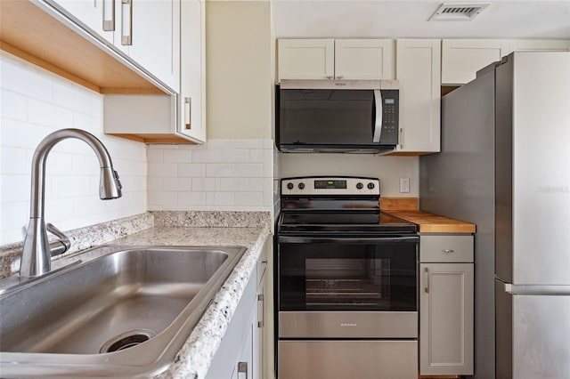 96 Boundary Blvd Unit 112, Rotonda West, FL 33947 - kitchen with appliances with stainless steel finishes, a sink, decorative backsplash, and white cabinetry