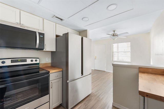 96 Boundary Blvd Unit 112, Rotonda West, FL 33947 - kitchen featuring appliances with stainless steel finishes, light wood finished floors, wood counters, and white cabinetry