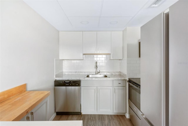 96 Boundary Blvd Unit 112, Rotonda West, FL 33947 - kitchen featuring appliances with stainless steel finishes, a sink, light wood-type flooring, tasteful backsplash, and white cabinets