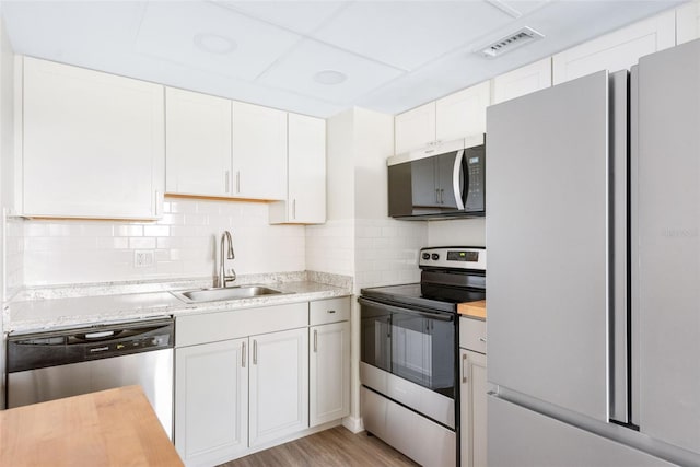 96 Boundary Blvd Unit 112, Rotonda West, FL 33947 - kitchen featuring stainless steel appliances, a sink, white cabinetry, tasteful backsplash, and light wood-type flooring