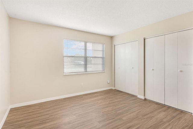 96 Boundary Blvd Unit 112, Rotonda West, FL 33947 - unfurnished bedroom featuring two closets, wood finished floors, and baseboards
