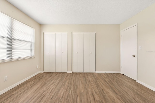 96 Boundary Blvd Unit 112, Rotonda West, FL 33947 - unfurnished bedroom with wood finished floors, multiple closets, baseboards, and a textured ceiling