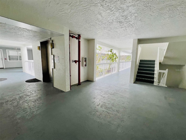 2380 N Beach Rd Unit 210, Englewood, FL 34223 - unfurnished living room with concrete flooring, stairway, and a textured ceiling