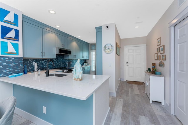 8405 Placida Rd Unit 406, Placida, FL 33946 - kitchen with a sink, tasteful backsplash, a peninsula, stainless steel microwave, and light wood-style floors