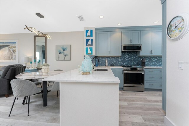 8405 Placida Rd Unit 406, Placida, FL 33946 - kitchen featuring stainless steel appliances, light wood finished floors, a sink, decorative backsplash, and a peninsula