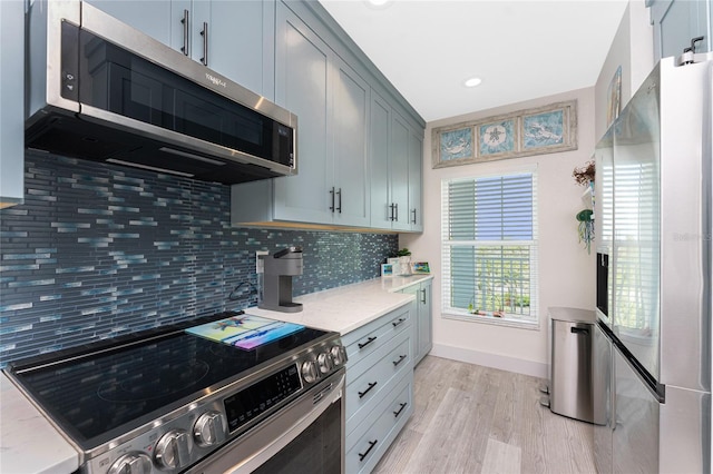 8405 Placida Rd Unit 406, Placida, FL 33946 - kitchen with appliances with stainless steel finishes, decorative backsplash, light wood-type flooring, light stone counters, and baseboards