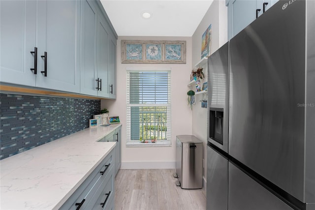 8405 Placida Rd Unit 406, Placida, FL 33946 - kitchen featuring stainless steel refrigerator with ice dispenser, light wood finished floors, backsplash, light stone countertops, and baseboards