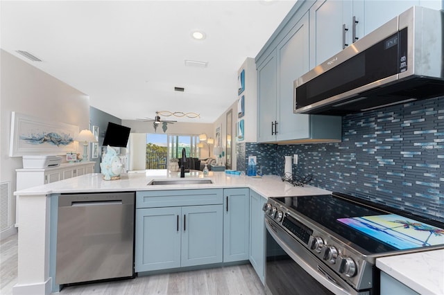 8405 Placida Rd Unit 406, Placida, FL 33946 - kitchen with appliances with stainless steel finishes, a sink, a peninsula, light wood-type flooring, and tasteful backsplash
