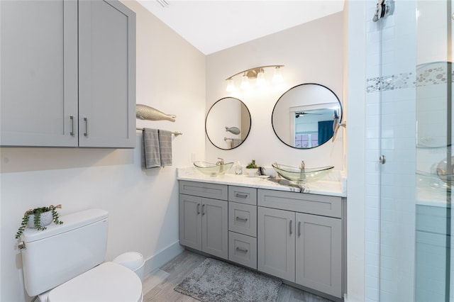 8405 Placida Rd Unit 406, Placida, FL 33946 - full bath with double vanity, toilet, a tile shower, wood finished floors, and baseboards