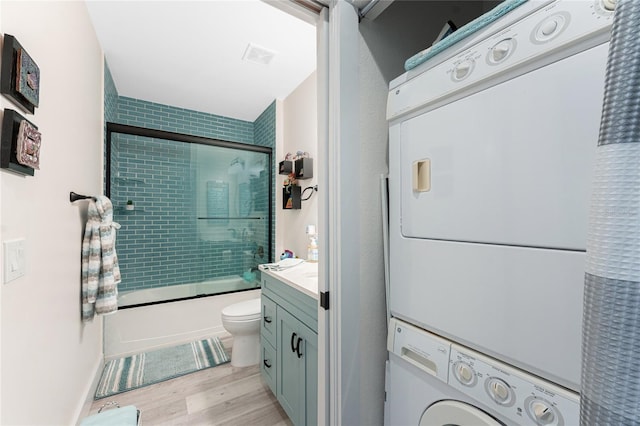 8405 Placida Rd Unit 406, Placida, FL 33946 - full bath featuring stacked washing machine and dryer, toilet, enclosed tub / shower combo, wood finished floors, and vanity