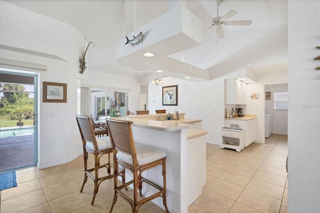 423 Boundary Blvd, Rotonda West, FL 33947 - kitchen with white cabinetry, light tile patterned floors, a towering ceiling, a breakfast bar, and light countertops