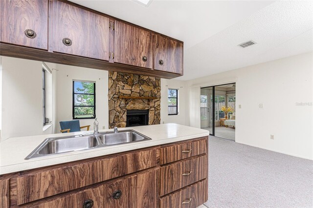 1337 Le Pera Rd, Englewood, FL 34223 - kitchen with a sink, light carpet, light countertops, a stone fireplace, and baseboards