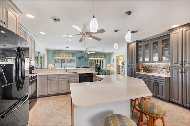 1040 Caples St, Englewood, FL 34223 - kitchen featuring black appliances, a sink, a kitchen bar, light countertops, and plenty of natural light