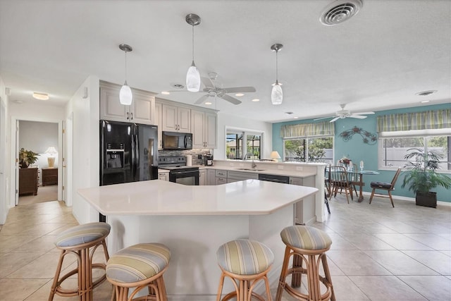 1040 Caples St, Englewood, FL 34223 - kitchen featuring black appliances, a ceiling fan, a kitchen breakfast bar, light tile patterned flooring, and recessed lighting